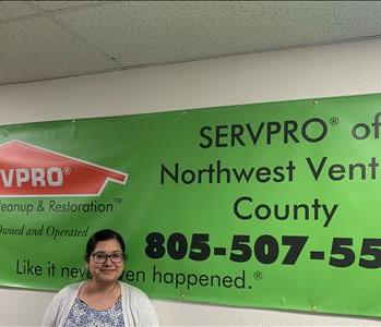 Female Employee Michelle Arias standing in front of a SERVPRO banner