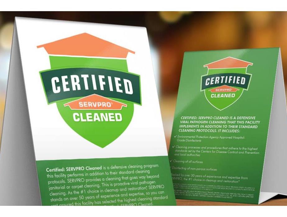 Two white and green table signs with Certified: SERVPRO Cleaned logo including description of services and key points.